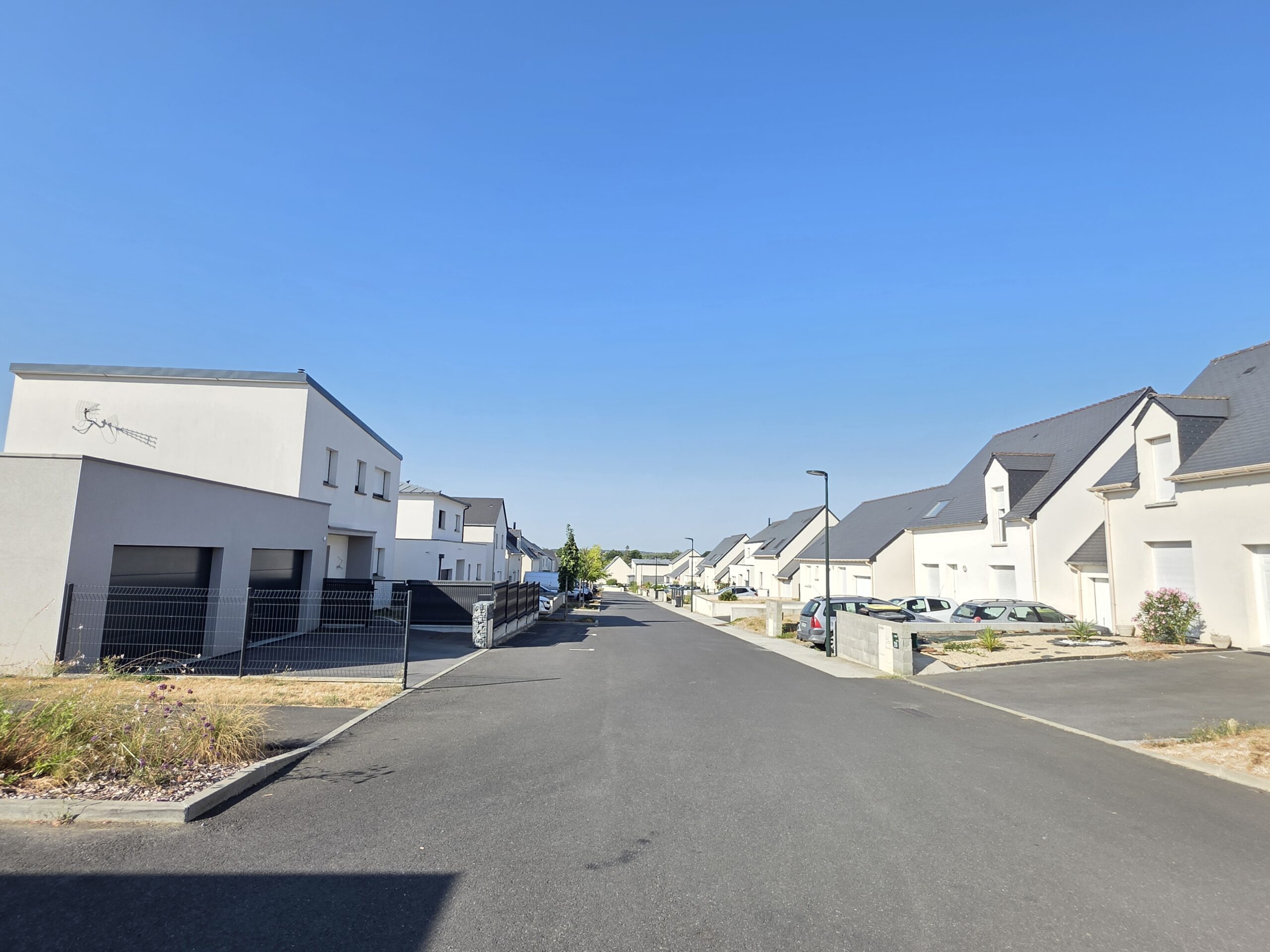 Rue bordée de maisons récentes dans un quartier résidentiel de Guignen